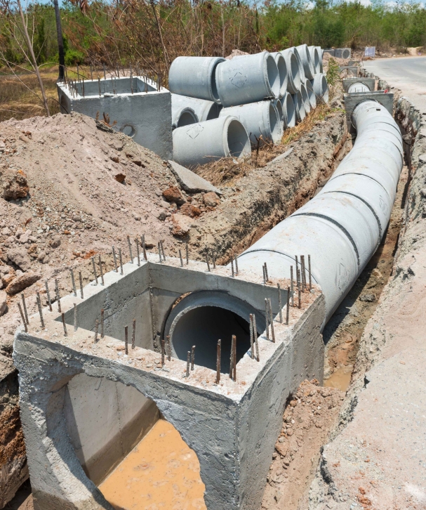 Cranes operate at a construction site during sunset, with workers actively engaged in building activities on the structure.