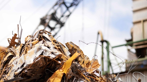Cranes operate at a construction site during sunset, with workers actively engaged in building activities on the structure.