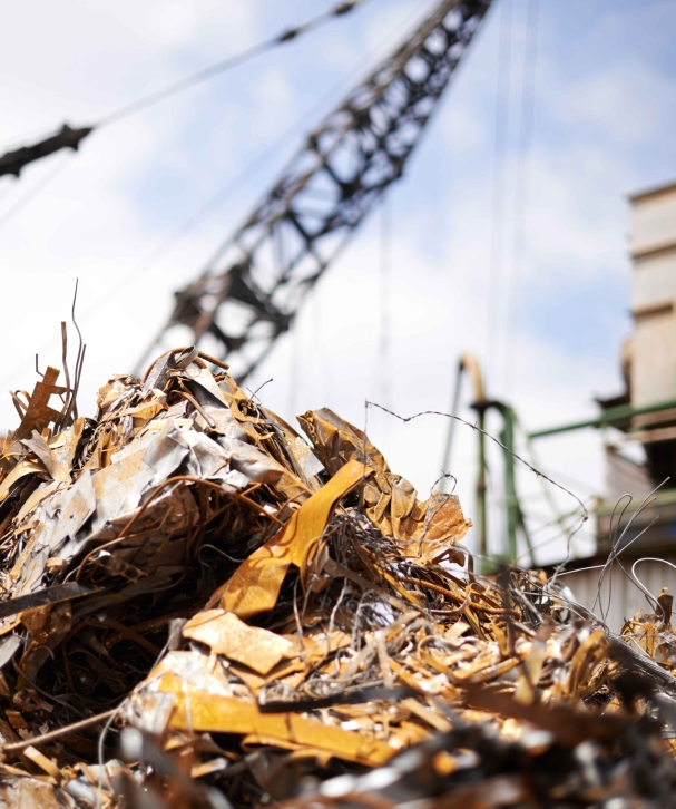 Cranes operate at a construction site during sunset, with workers actively engaged in building activities on the structure.