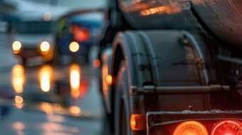 Cranes operate at a construction site during sunset, with workers actively engaged in building activities on the structure.